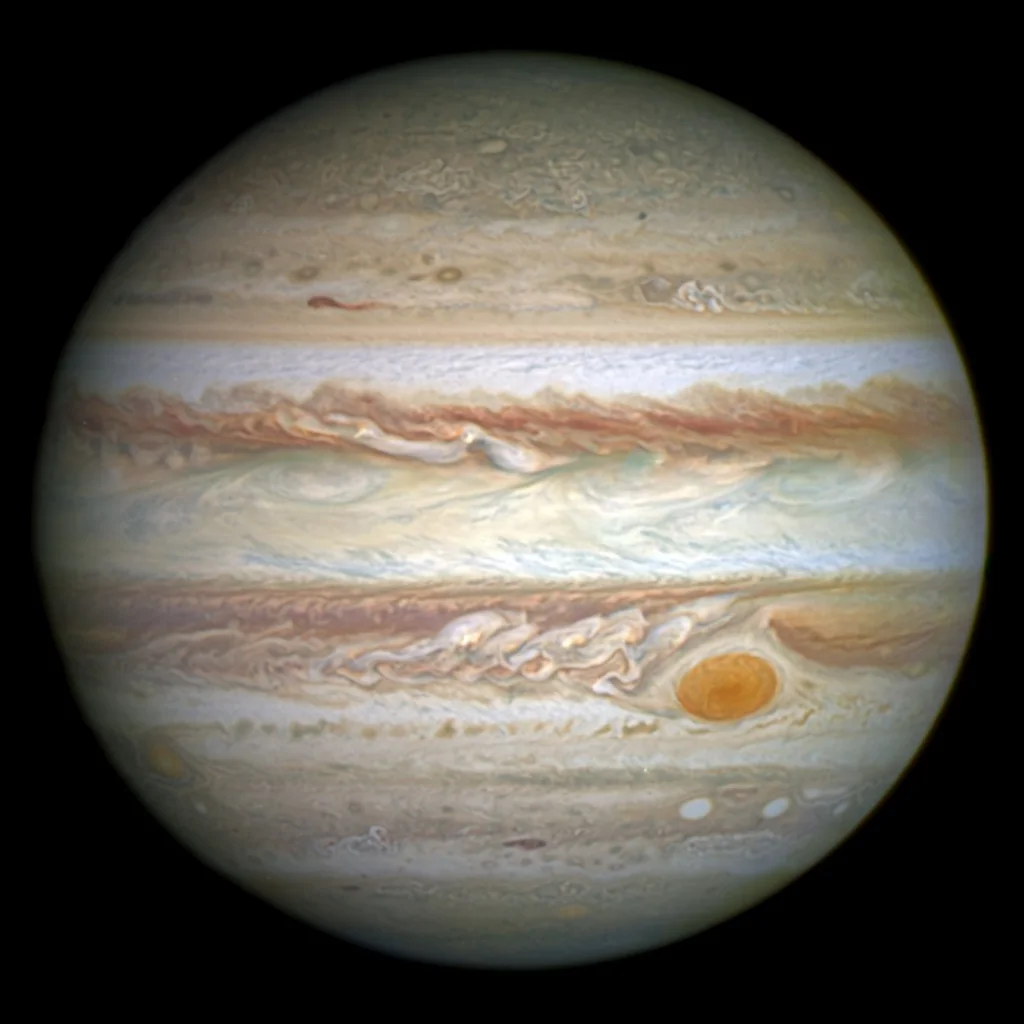 Jupiter with banded cloud belts and the Great Red Spot, four Galilean moons visible beside it.