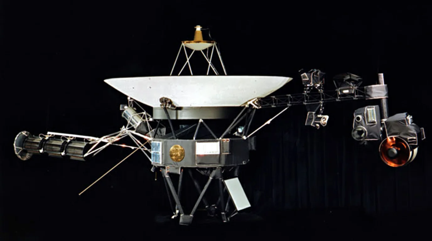 Voyager 1 spacecraft against the cosmic void, dish antenna pointing back toward a distant Earth.